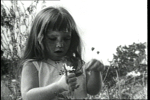 A little girl holds a daisy in a black and white photo