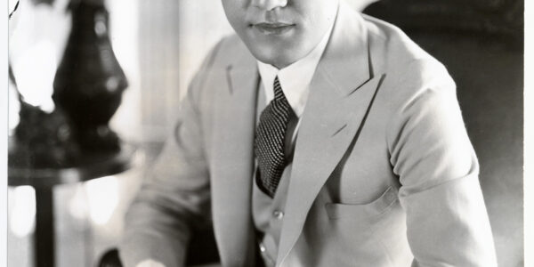 Photo in black-and-white of screen star Sessue Hayakawa, looking left of camera and sitting
