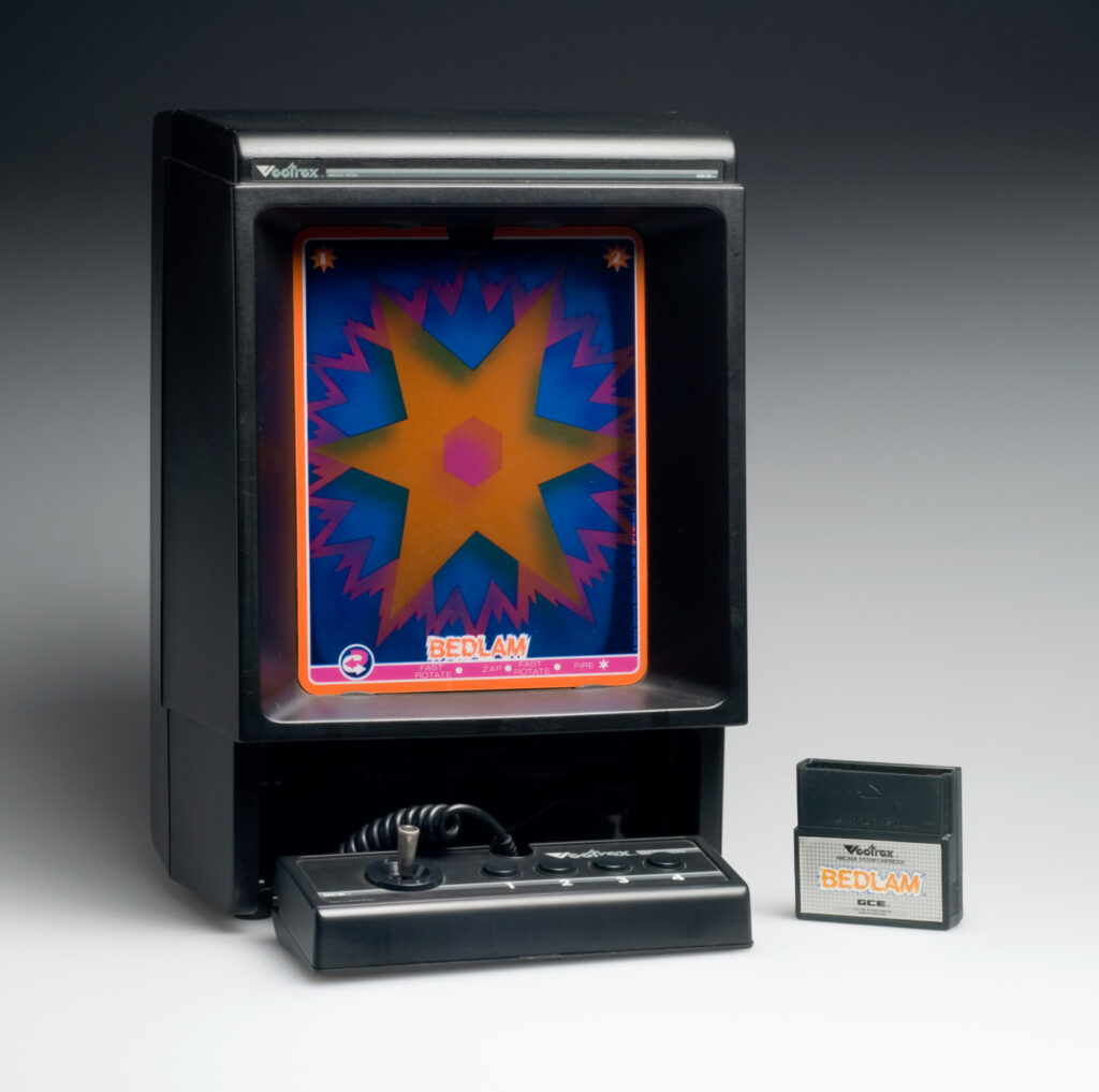 Video game console from 1982, with the image of a bursting yellow star against a purple background on the screen, and a game cartridge next to it