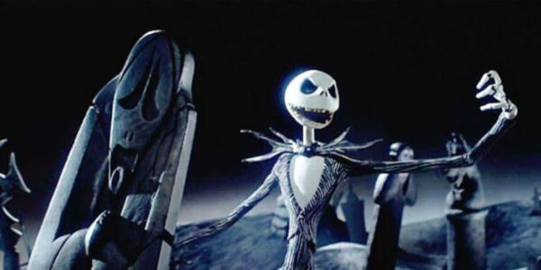 Jack Skellington holding up one claw in a graveyard and singing