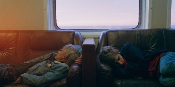 Two sleeping men on a boat, the morning sun entering a window behind them