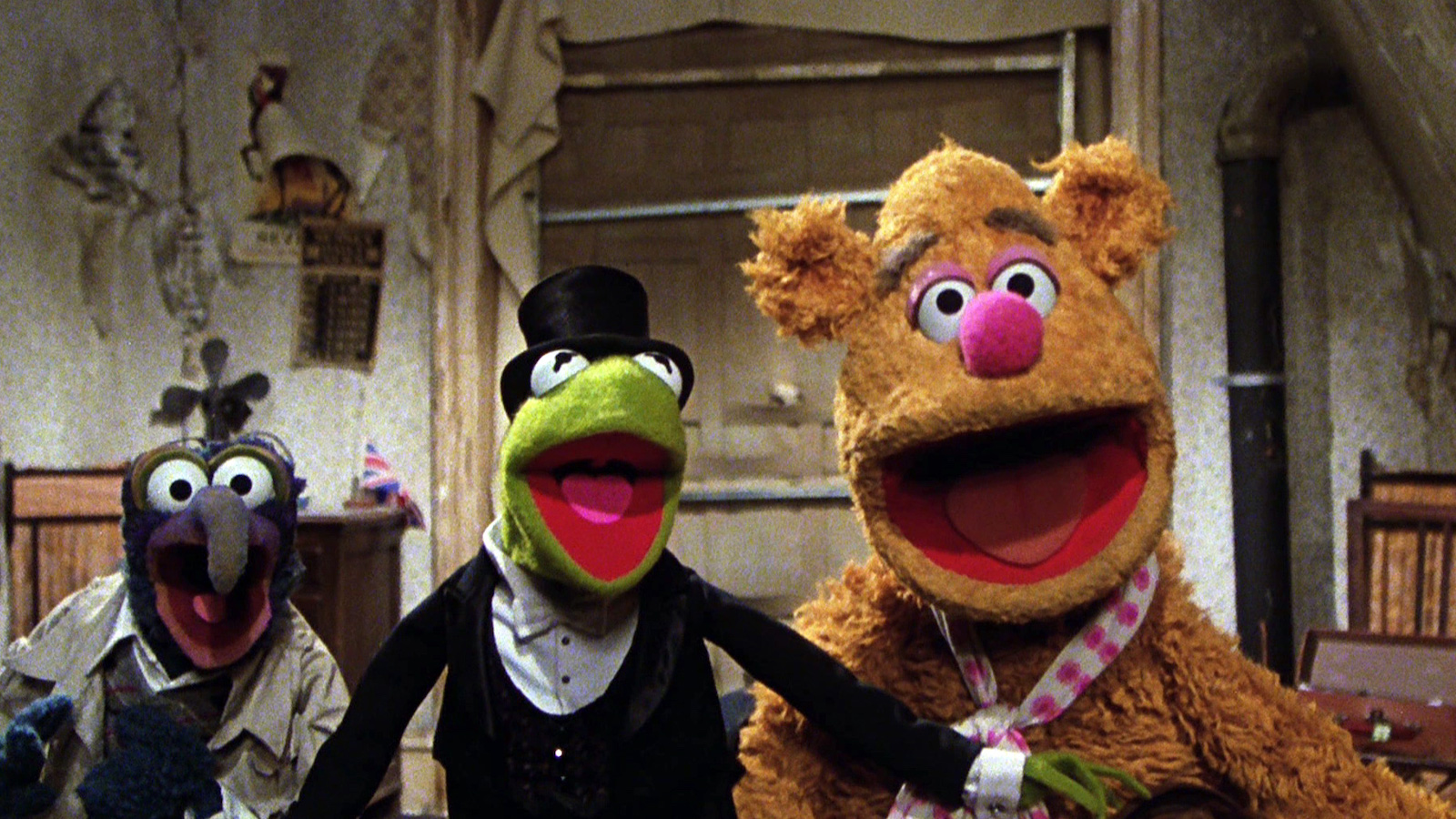 Three muppets, Gonzo, Kermit, and Fozzie Bear look at the camera, their mouths open