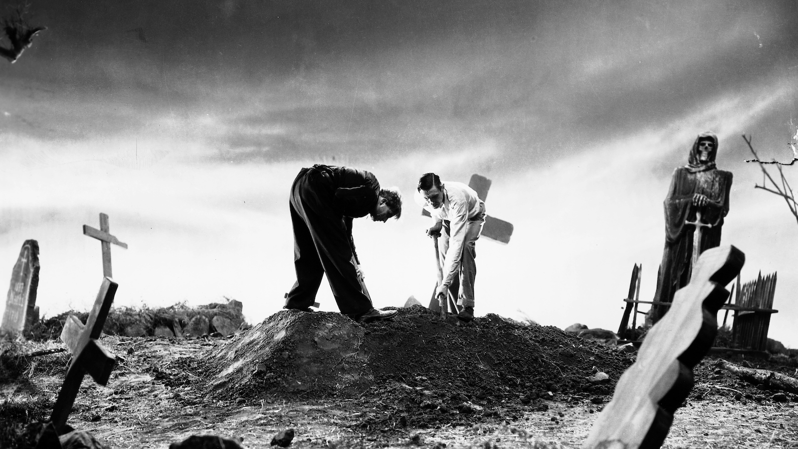 Two men dig up a grave on an early morning hillside