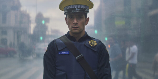 A policeman looks disturbed as he stares directly at camera from the middle of a street