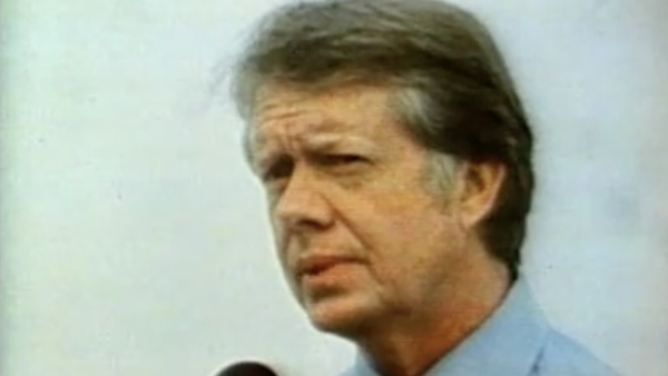 Former President Jimmy Carter in close-up giving a speech in front of a microphone