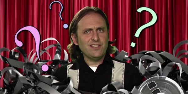 A goofy man looking into camera and surrounded by question marks and film reel cans