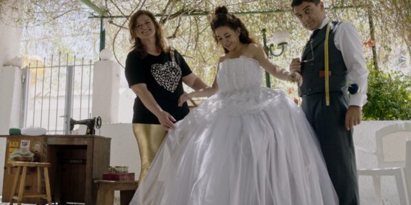 A woman tries on a wedding dress with the help of her tailor