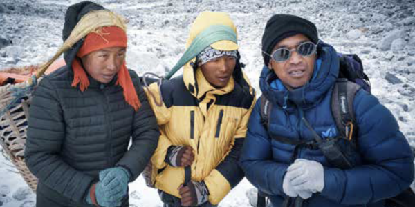 Three men wearing heavy coats for a climbing expedition