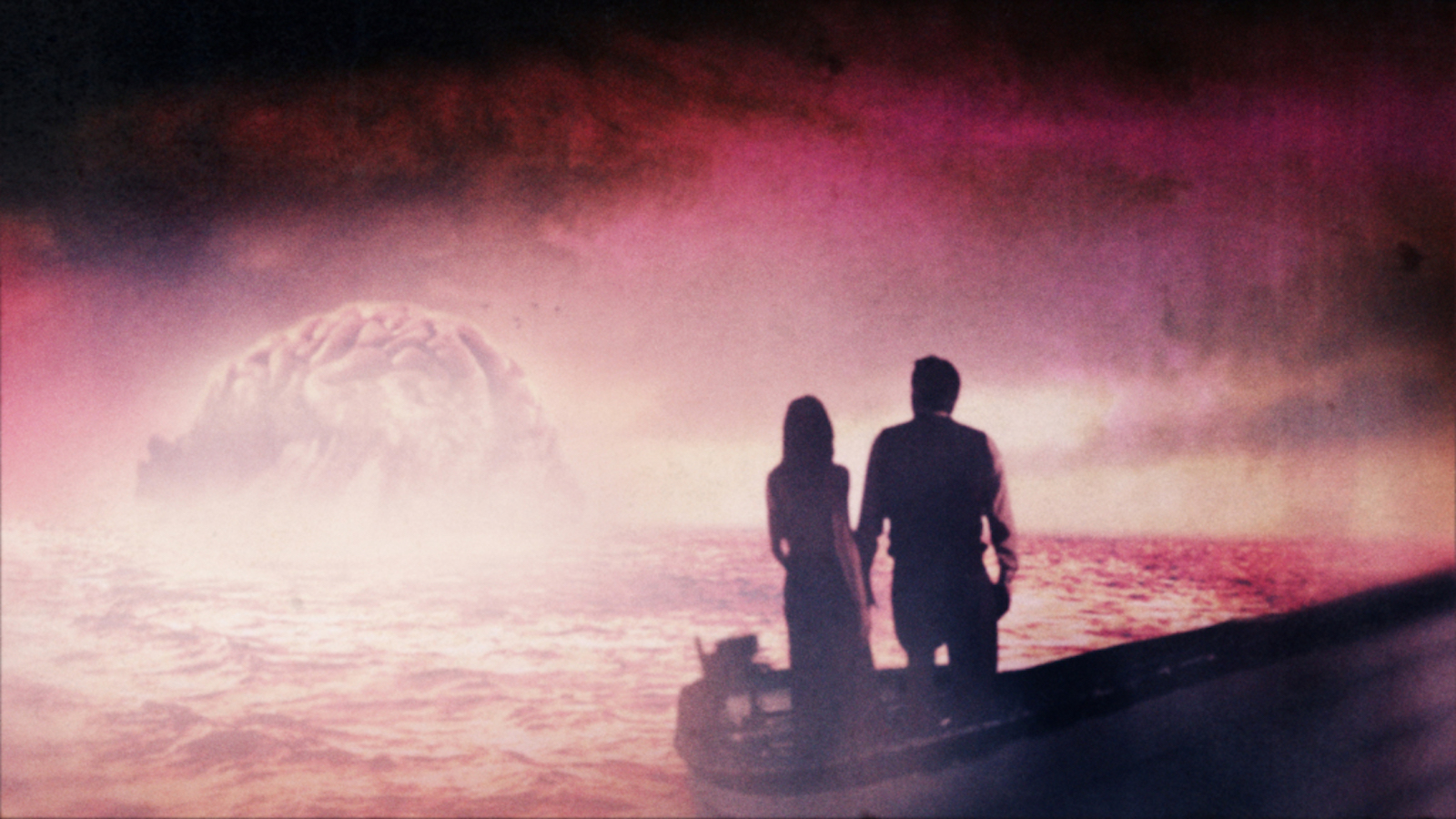 Two figures silhouetted standing on a rowboat in front of a red mist, with a gigantic cloud shaped like a brain in the distance.