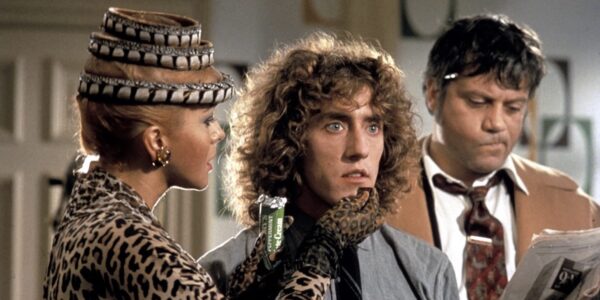 A young man with curly brown hair stares into the distance, flanked by his mother, in a leopard print jacket, holding his chin gently, and his father on his left