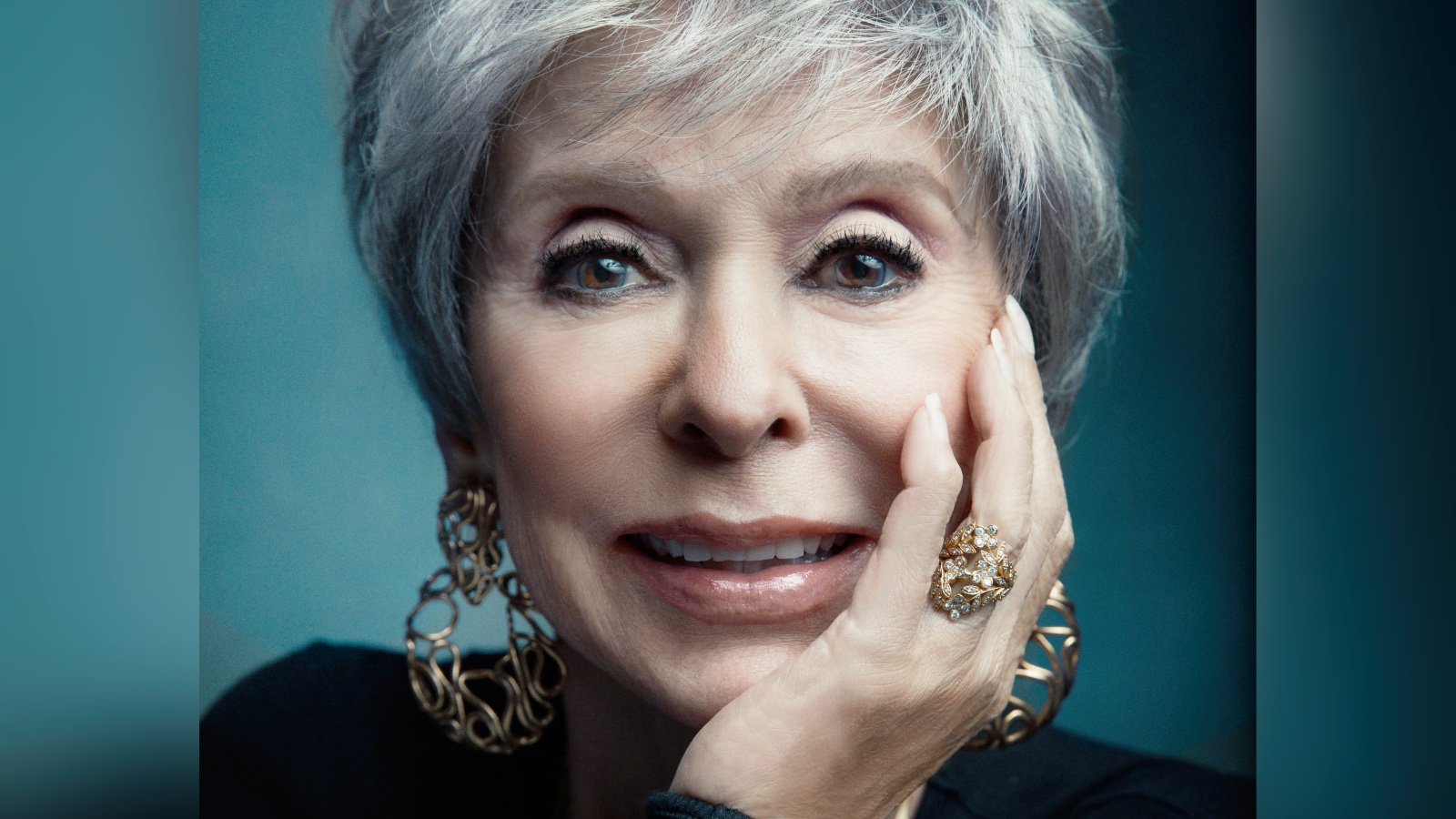 A close-up of the legendary star Rita Moreno, her face resting on her hand.