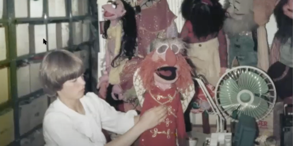 A photograph from the 1970s of puppet maker and puppeteer Bonnie Erickson working on a red-headed muppet with its mouth open.
