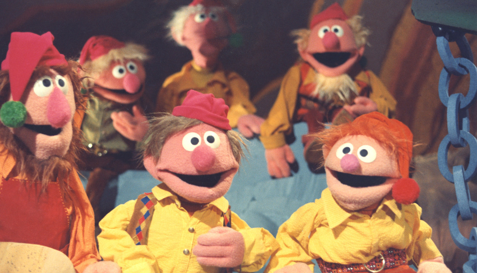 Muppet elves in yellow shirts smiling at the camera