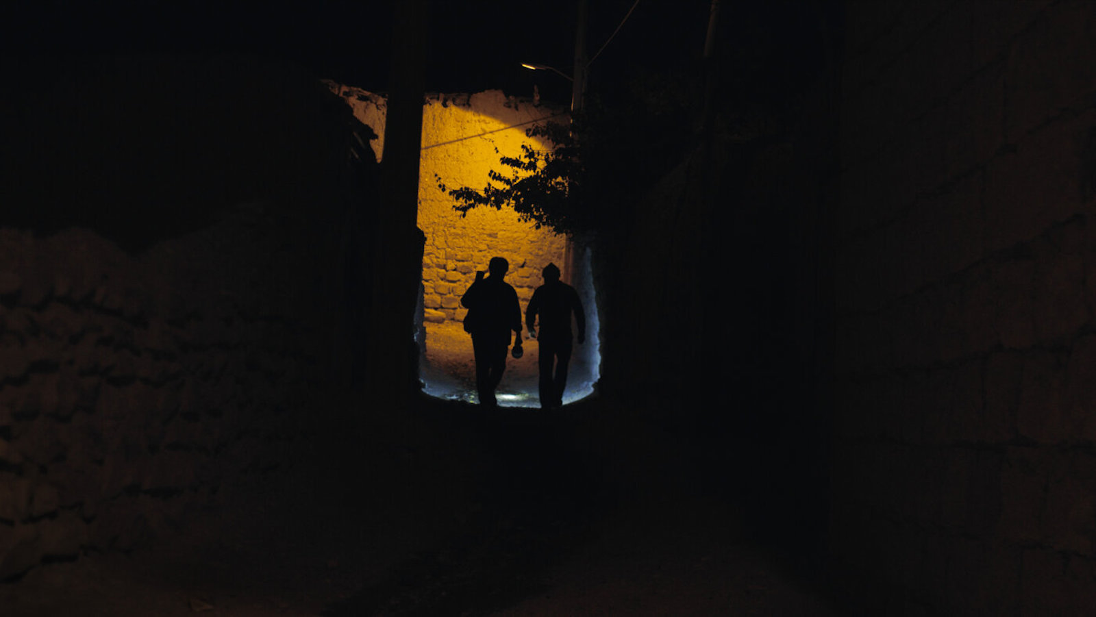 Two people silhouetted in dark nighttime street