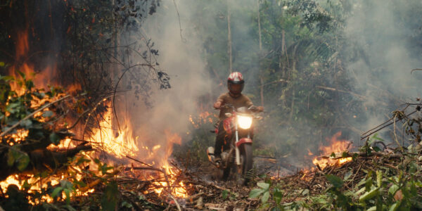 An invader rides his motorcycle through the rainforest fire blaze.