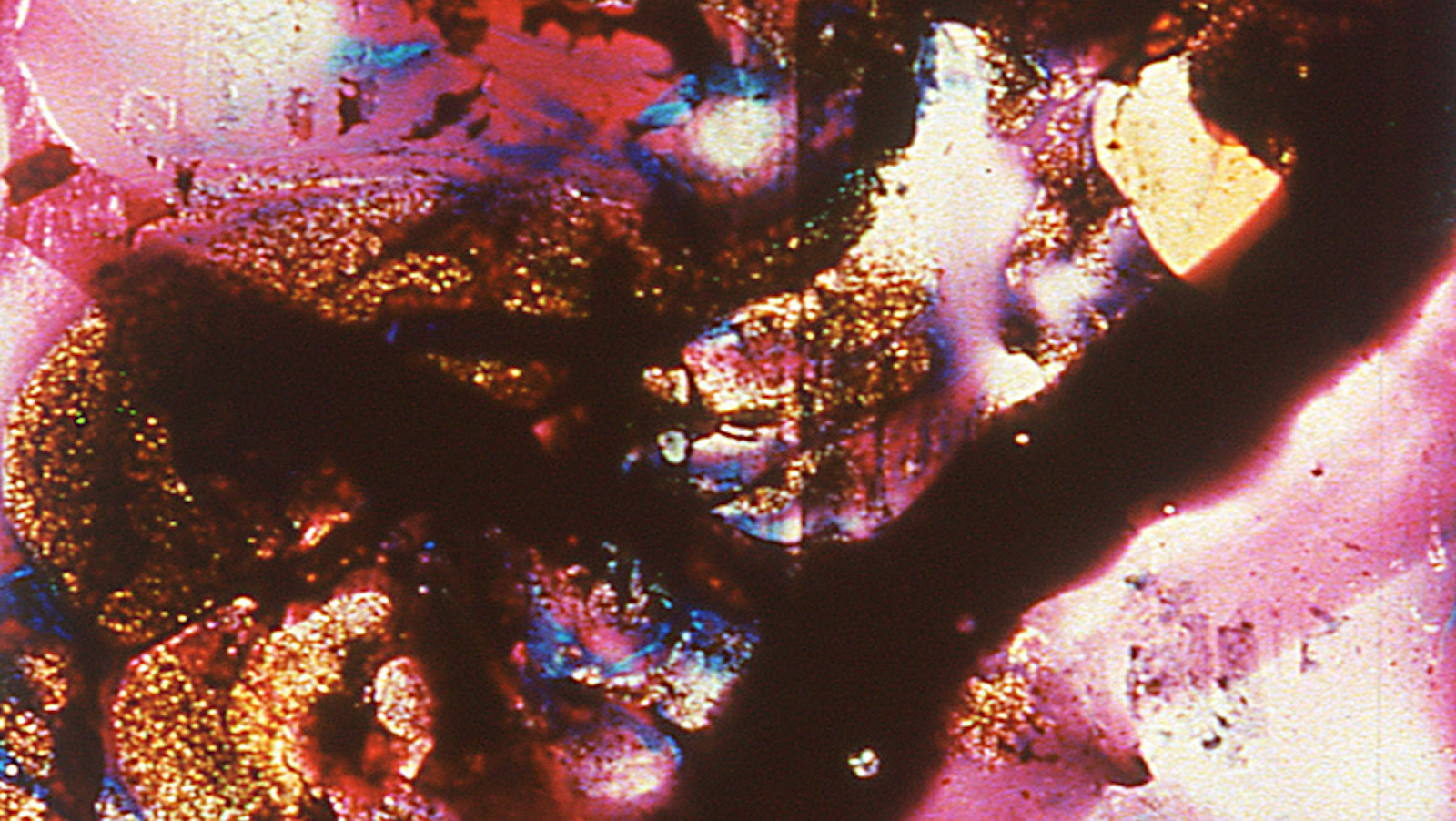 An abstract image of pink, blue, and gold paint on glass