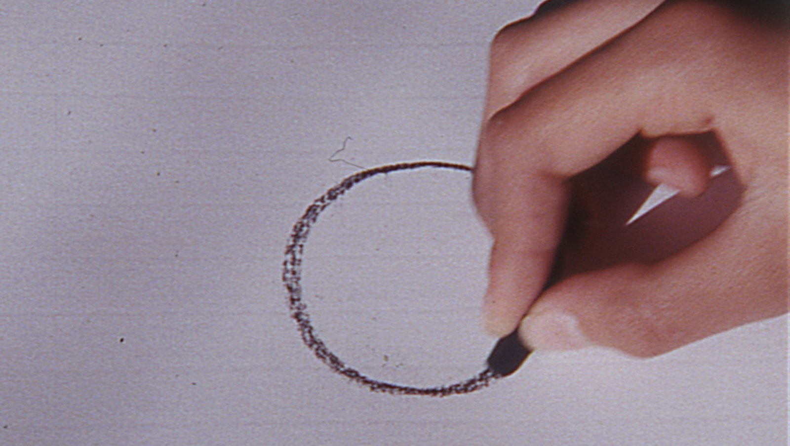 A hand draws a circle on paper