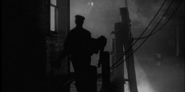 a man in silhouette against a misty dock at night