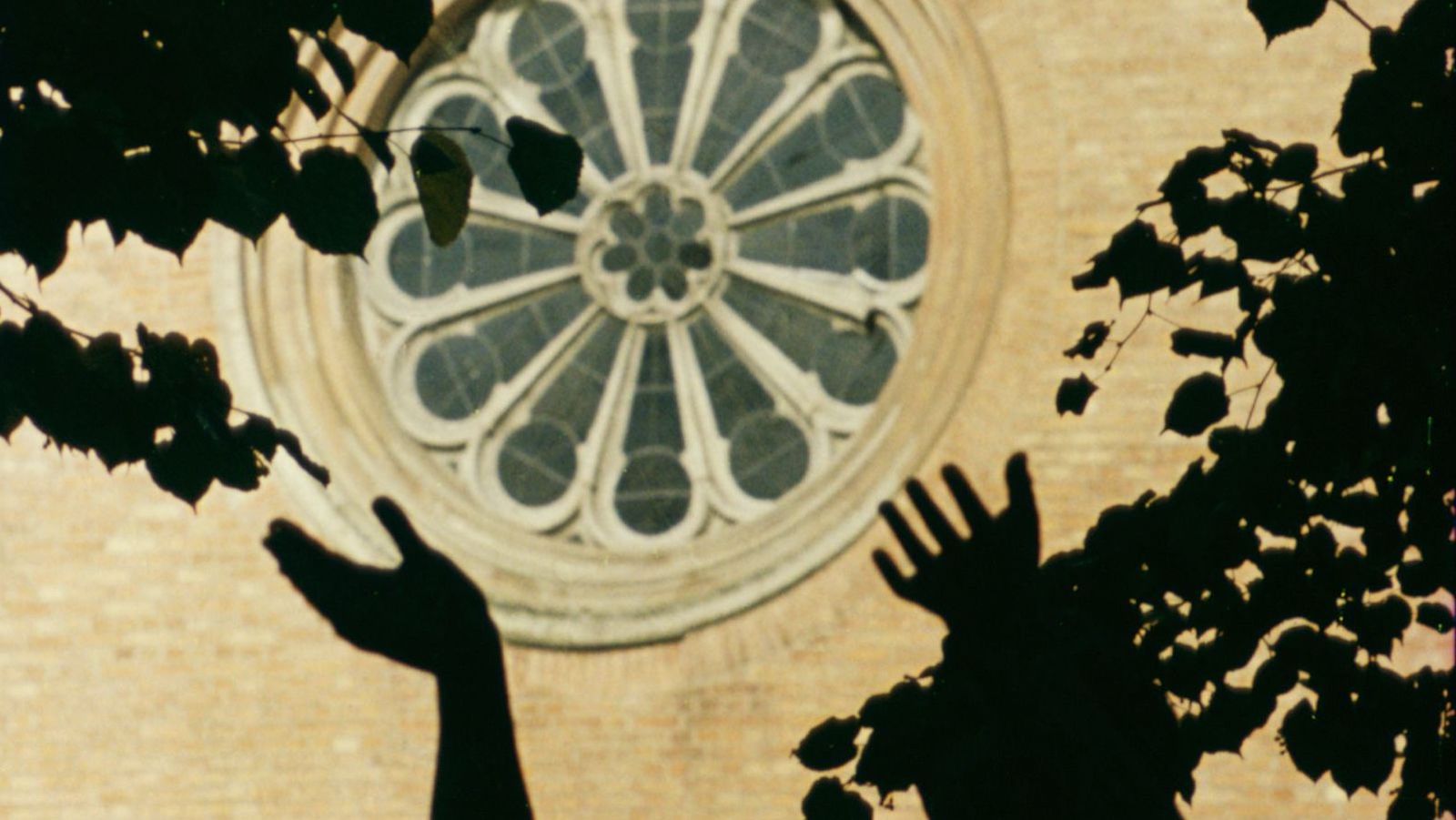silhouettes of hands reaching for a church window