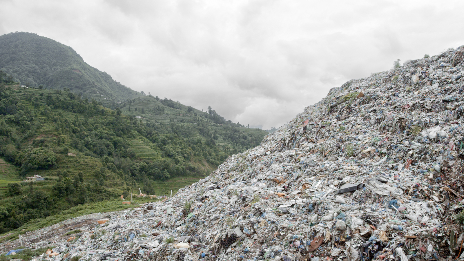 An image of a gigantic trash heap, as big as the green mountain next to it