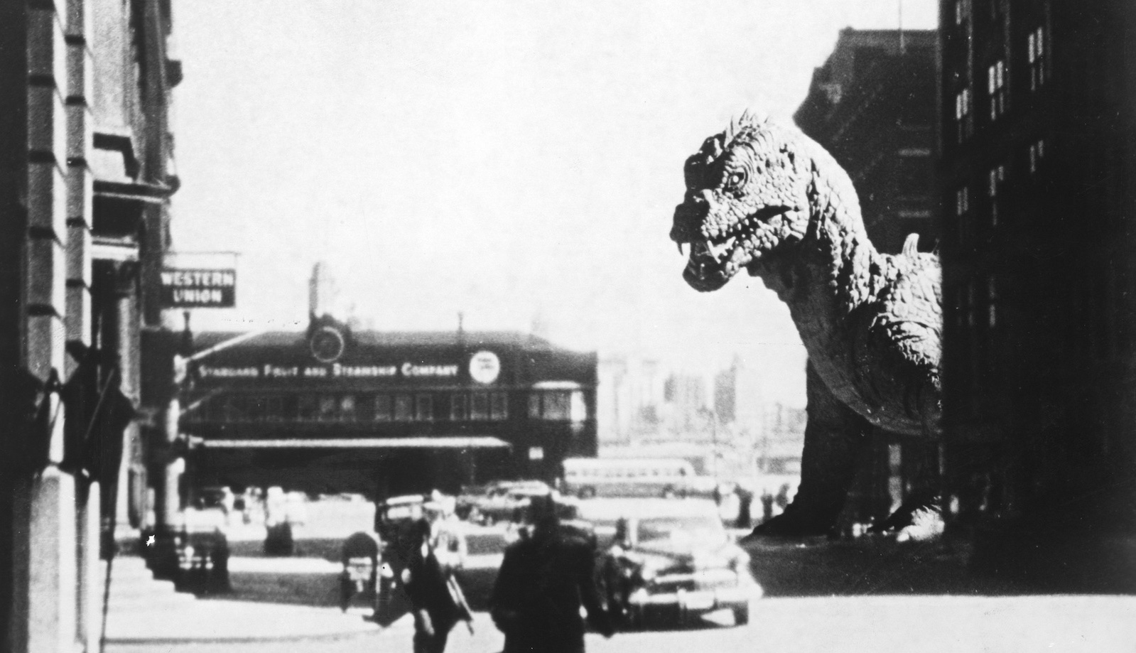 A black and white image of a gigantic dinosaur peeking out from the corner of a city street with people running in panic