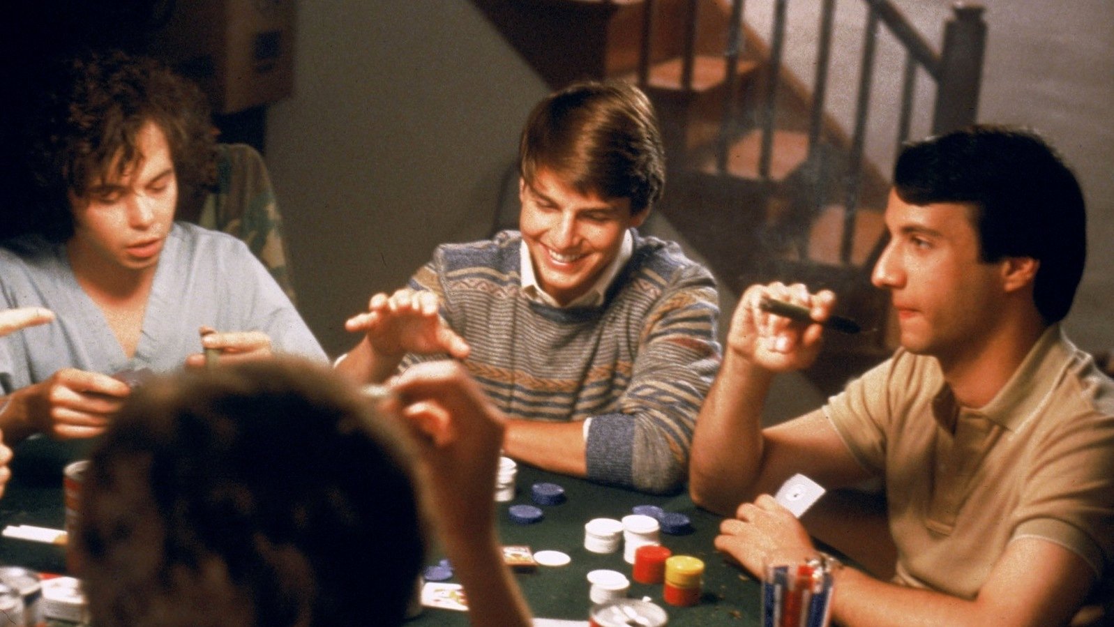 A group of teenage boys play poker and smile, having fun.