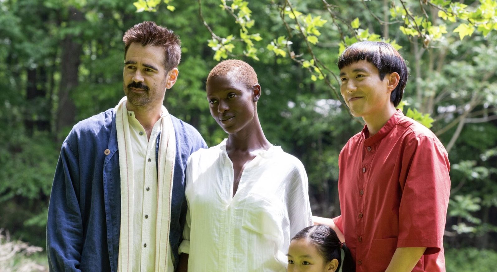 A family of four, including a man playing an android, dressed in a red shirt, stands in a backyard garden and smiles