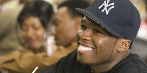 A close-up of a smiling man in a New York Yankees baseball cap