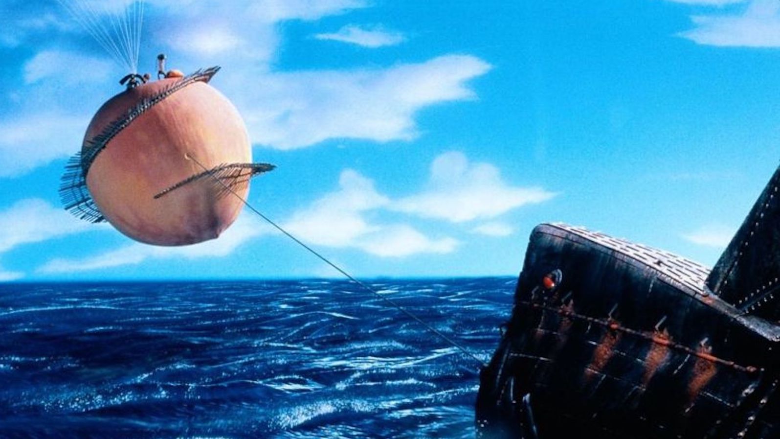 A giant peach floats in the sky over the sea connected to a rope tethered to a boat