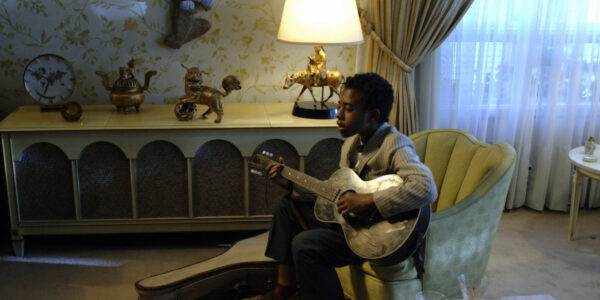 a young boy holds a guitar and sings while sitting in a living room