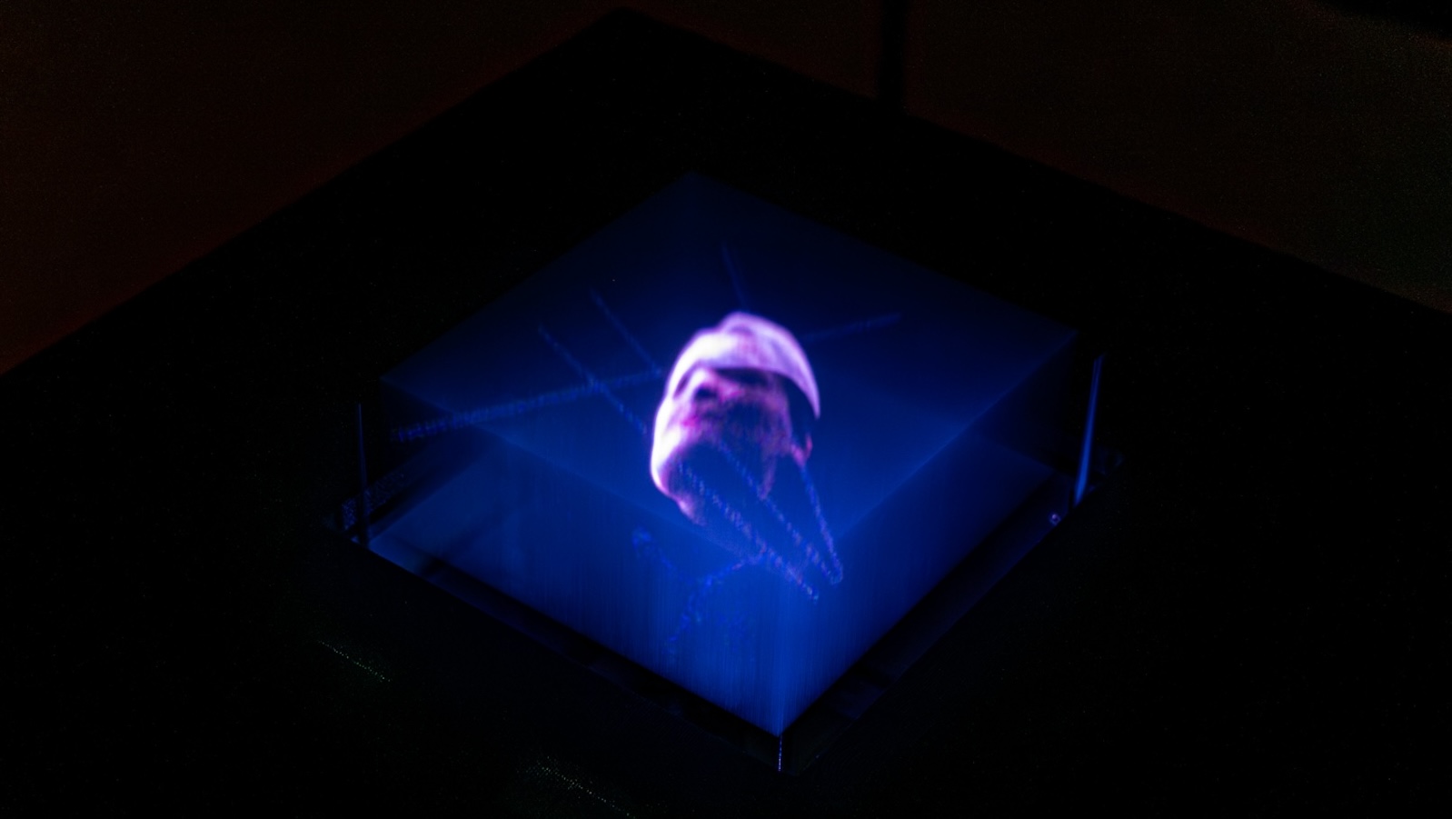 A hologram of a face floats in the middle of a blue digital box