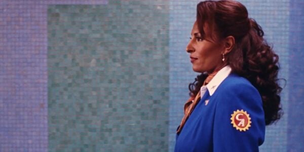 A woman in an airline attendant blue suit in profile against a colorful tiled wall at an airport