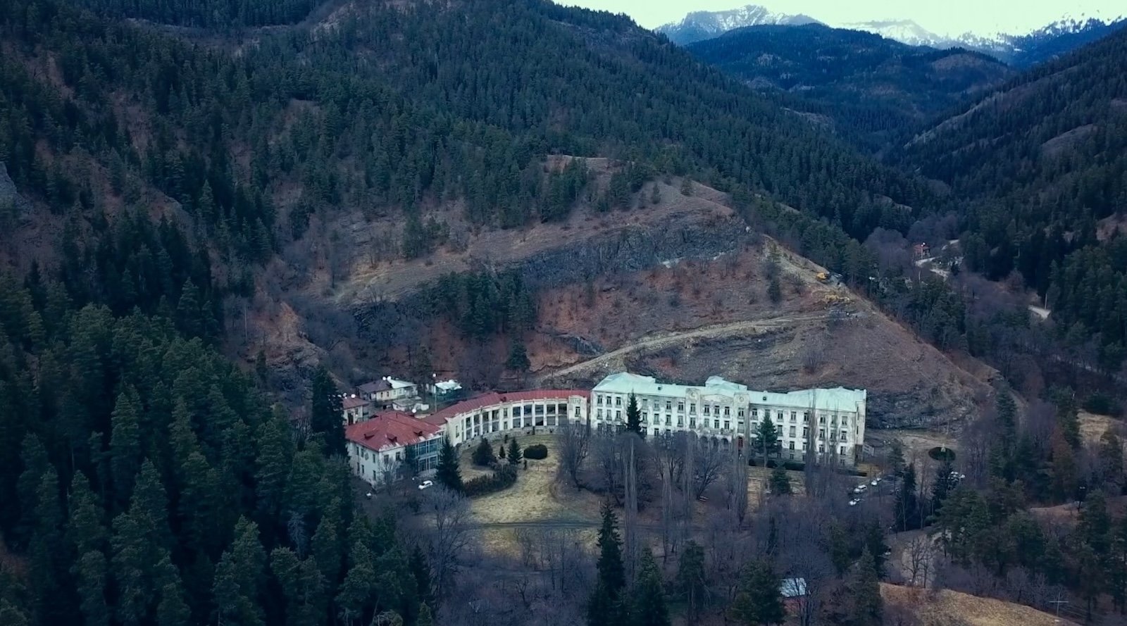 A vast building nestled deep in a mountainous environment, seen from a distance