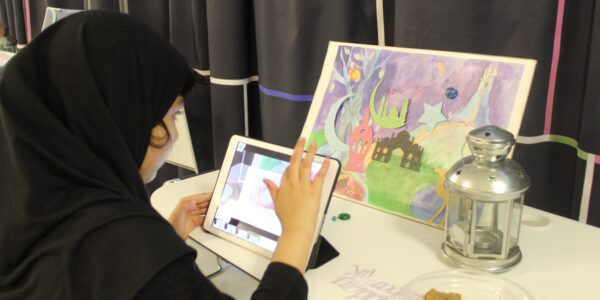 A young girl in a hijab touches the screen of an iPad making animations