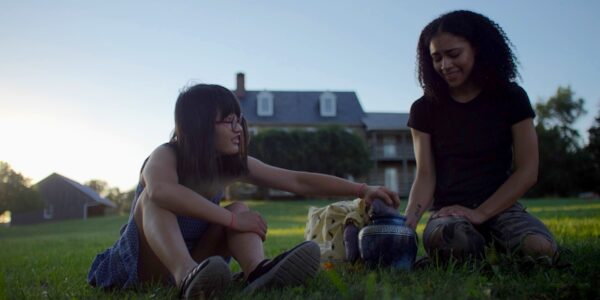 Two young people sit on a lawn