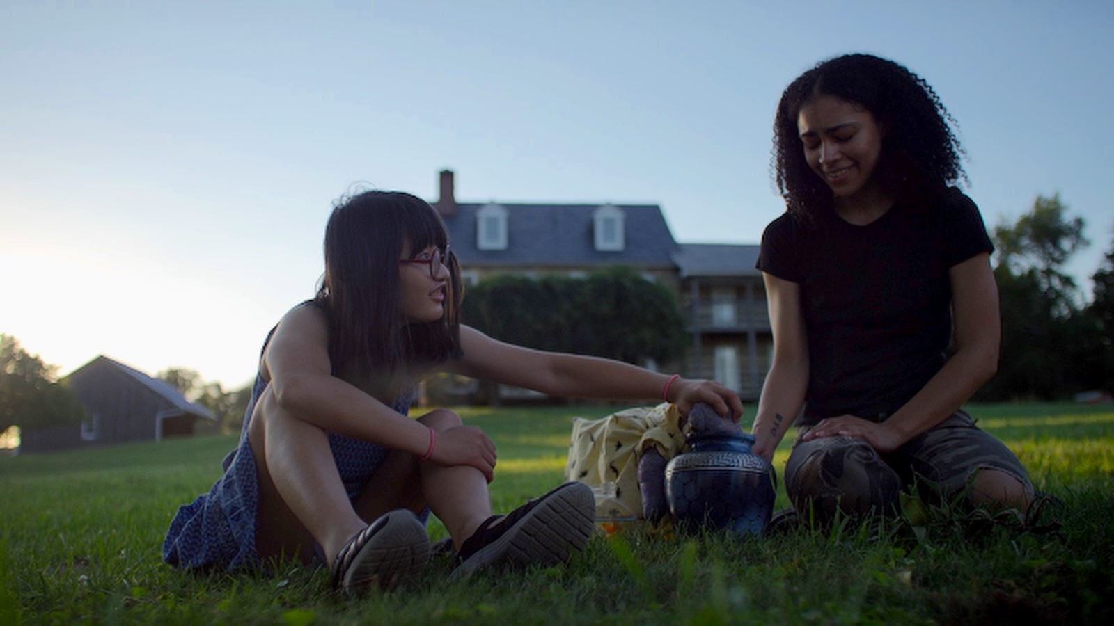 Two young people sit on a lawn