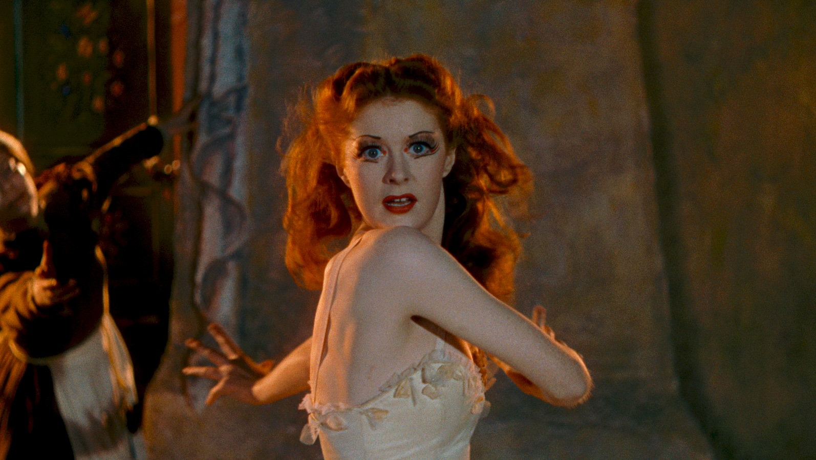 A woman with fiery red hair dances, her head turned toward the camera
