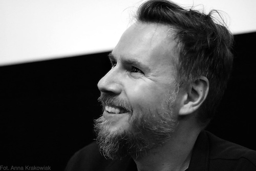 A man with a beard smiles in profile