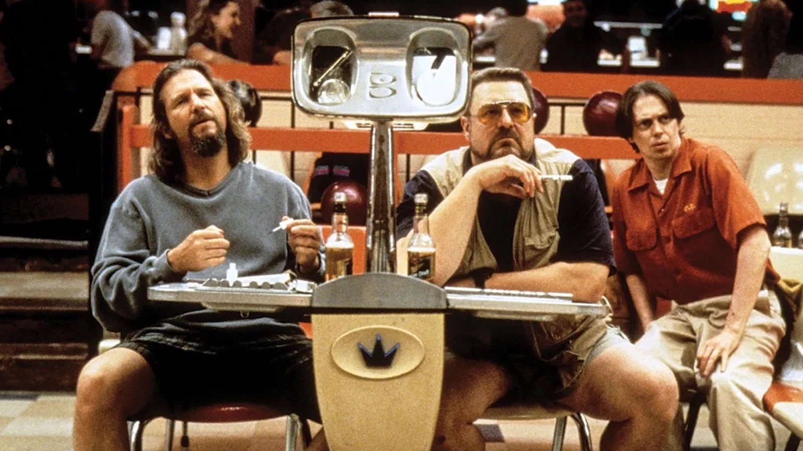 Three men sit at a bowling alley lane booth, two wearing shorts and one in khakis looking past us quizzically.